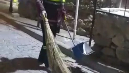 Hem çevreyi temizliyor hem de sokak kedisine süpürgesi ile masaj yapıyor